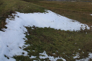 A snowy hill with grass and grass