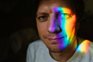 Smiling man with rainbow light on face