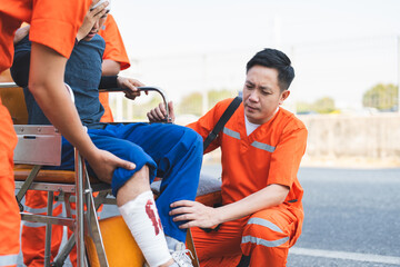 Asian male EMS paramedics or emergency medical technicians in orange uniforms performing first aid...