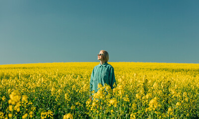Woman standing amidst flowers in rapeseed field