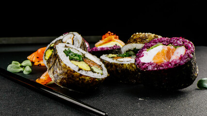 Variety of types of sushi with red caviar, fish, Philadelphia cheese close-up. Set of delicious Japanese sushi rolls on a black background. The concept of advertising healthy and tasty seafood food.