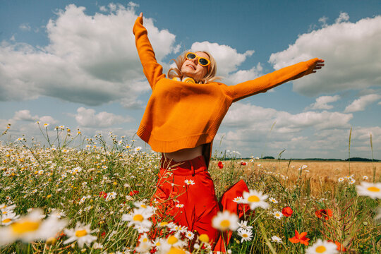 Carefree woman jumping with arms raised in chamomile field