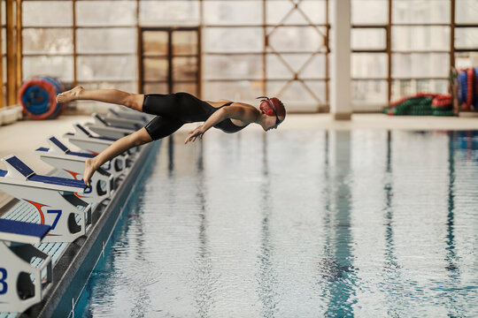 A young female swimmer is diving and jumping into the swimming pool on her training.