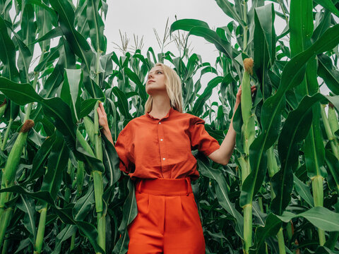 Thoughtful woman standing in corn field