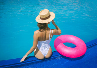 Woman in swimwear relaxing near inflatable swim ring by pool