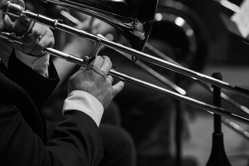  A fragment of a trombone in the hands of a musician close-up in black and white - 723120718