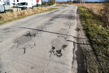 A damaged and hole-punched aflat road in the countryside.