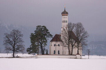 Fototapeta na wymiar Iglesia de St. Coloman un día nublado de invierno, en Schwangau, Alemania