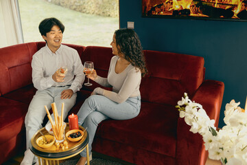 Smiling friends enjoying in conversation and drinking wine during holiday party at home