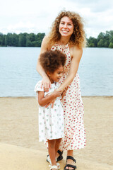 A young mother plays with her daughter on the beach near the lake.