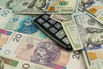 Background made of Polish zloty banknotes, calculator and USD dollar banknotes