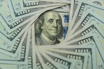 A 100 USD banknote surrounded by US dollars banknotes