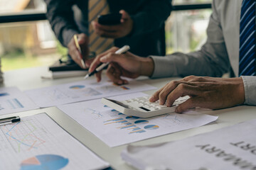 Teamwork with business people analyzing cost graphs on a table at a business conference room and office workers working with project planning documents on a conference table, close-up photography