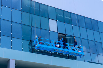 Installation teams working on gondola lift construction for install glass facade at office building 