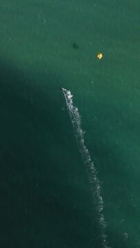 Drone vertical shot of kite surf man on the water escaping from the dark