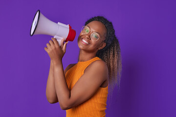 Young cheerful beautiful African American woman entrepreneur with megaphone in hands announces...