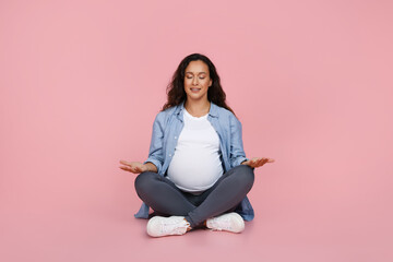 Portrait of positive pregnant woman meditating on floor