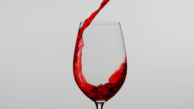 Close up studio shot of beautiful goblet isolated on white background in studio. Red wine pouring into a wine glass from the bottle creating wave splashes.