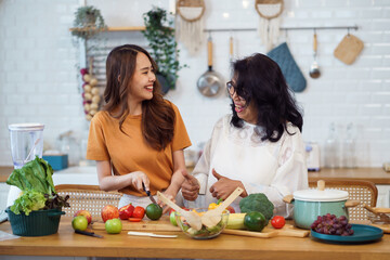 Asian lovely family in the kitchen. Beautiful female enjoy spending leisure time with senior elderly mom while cooking salad and food healthy