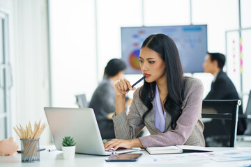 Happy young confident businesswoman sitting at the office table with group of colleagues