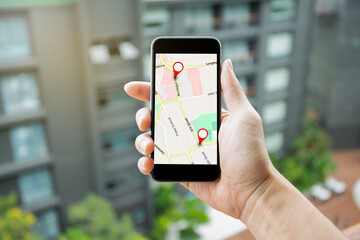 Man hand holding smartphone with GPS Map to Route Destination network connection. Location Street Map with GPS Icons Navigation and Red icon of location. Online Navigation Concept.
