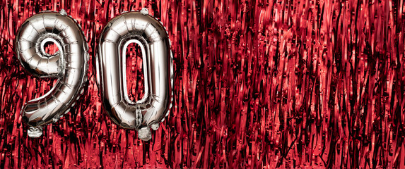 Silver foil balloon number ninety. Birthday or anniversary card with the inscription 90. red tinsel...