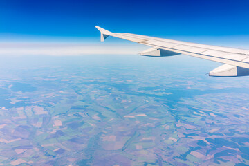 Aerial view from airplane window above green ground. View from the airplane window with beautiful clouds at sunrise