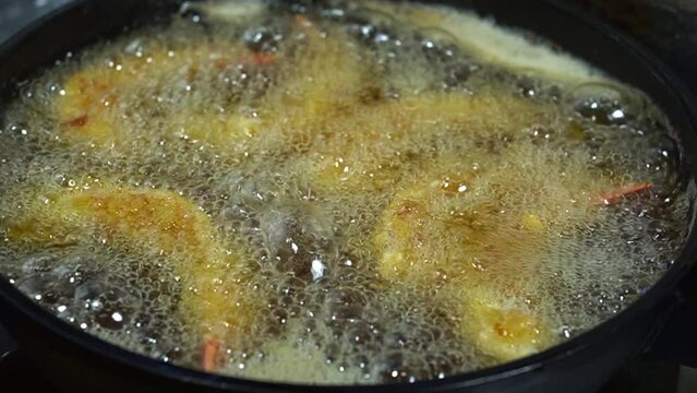 フライパンでエビを揚げてエビフライを作っているシェフ