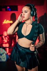 Pretty young woman DJ wearing headphones and playing music. Real vertical photography.