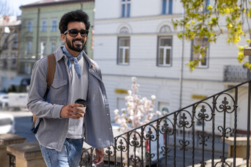 Smiling positive hindu man with a cup of coffee in hands