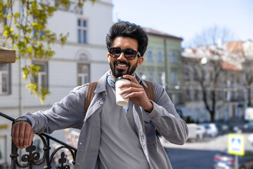 Smiling positive hindu man with a cup of coffee in hands