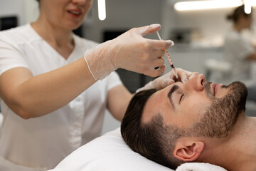 Cosmetologist making mesotherapy injections to mans face
