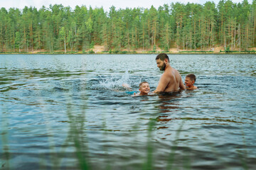 father and children swimming in forest lake. Man teaching son to swim