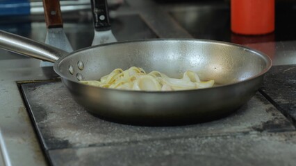 The cook is preparing pasta with squid and shrimp, the chef is cooking in the kitchen, a frying pan with pasta and sauce, cooking in a restaurant, close-up.