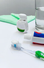 Limpieza dental. Salud bucodental. Productos de higiene bucal, cepillo, hilo dental, crema o pasta de dientes, agua y toallita de baño. Superficie blanca y espacio para copiar.