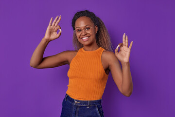 Young successful beautiful African American woman shows OK gesture with both hands answering...