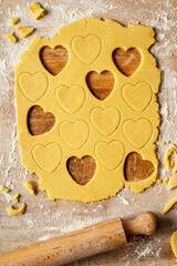 Sweet shortcrust pastry laid out on a pastry board, ready for use. Heart-shaped shortcrust biscuits. The ingredients are eggs, sugar, butter and flour. Top view.