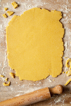 Sweet shortcrust pastry laid out on a pastry board, ready for use. The ingredients are eggs, sugar, butter and flour. Top view.