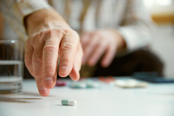Close-up of male hands taking pills, vitamins, meds at home. Blurred background, focus on hands....