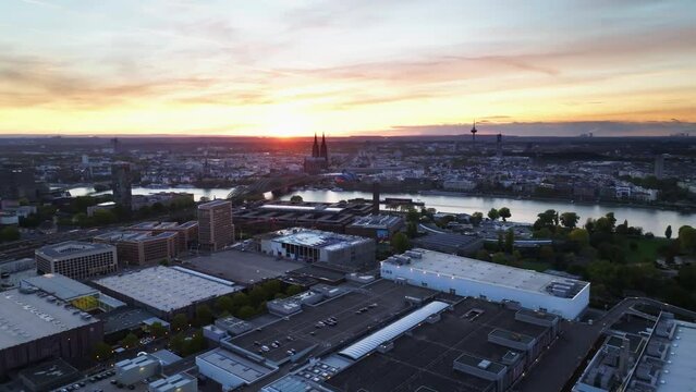 Aerial flight with sun backlit over the city of cologne with sunset and colorful sky. The Rhine divides the city. Drone move right.