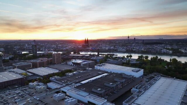 Aerial flight with sun backlit over the city of cologne with sunset and colorful sky. The Rhine divides the city. Drone move left.