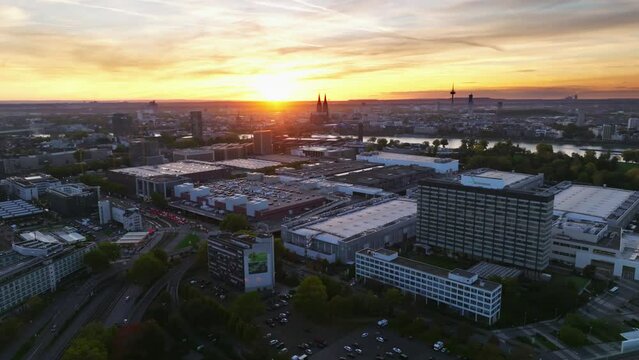 Aerial flight with sun backlit over the city of cologne with sunset and colorful sky. There is evening traffic on Highway. Drone move left
