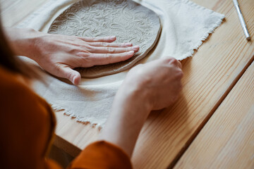 Hand moulding from white clay, Potter moulding an openwork plate. A woman potter in the workshop passionately moulding a product. - obrazy, fototapety, plakaty