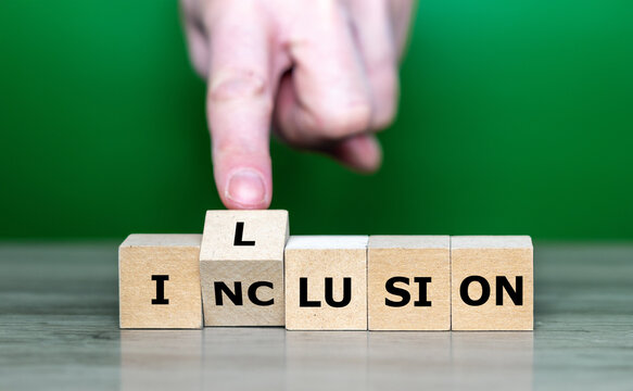 Hand turns wooden cube and changes the word inclusion to illusion. Symbol for a failed inclusion.