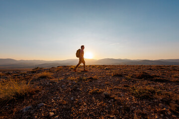 solo trip. a man with a backpack walks along the path against the backdrop of mountains. hiking in...