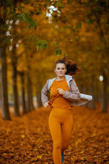 elegant female in fitness clothes in park jogging