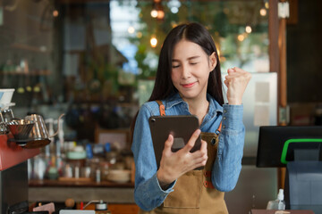 Young businesswoman, owner of an Asian cafe, in navy blue shirt wearing  brown apron, is looking...
