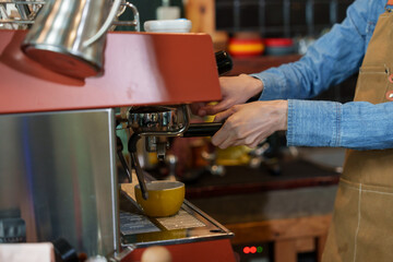 Hands of businessman barista employee young Asian woman owning small coffee shop business Finely grind coffee beans make coffee yellow coffee cup stood behind coffee maker counter Inside coffee shop