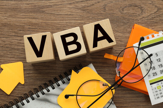 VBA on wooden cubes near calendar and notepad