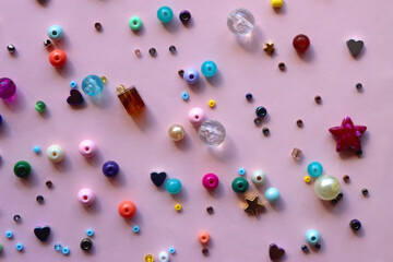 Various colorful beads on bright pink background. Top view.